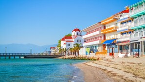 A coastal building with balconies, a beach in the foreground, and a clear sky. - Hotel Strass (Katerini)