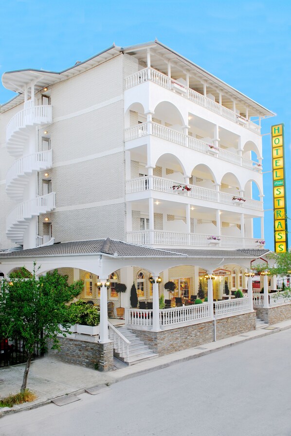 A multi-story hotel with a white facade, multiple balconies, and a covered entrance area.