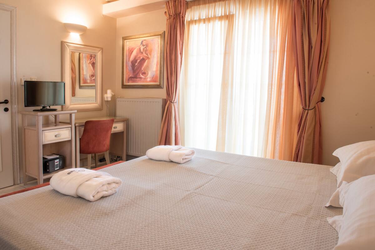 Una habitación de hotel con una cama, un escritorio con computadora, una silla y televisión.