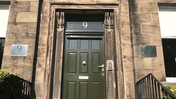 Un edificio de piedra con una puerta verde marcada con el número 9, un buzón pequeño y una reja de metal.