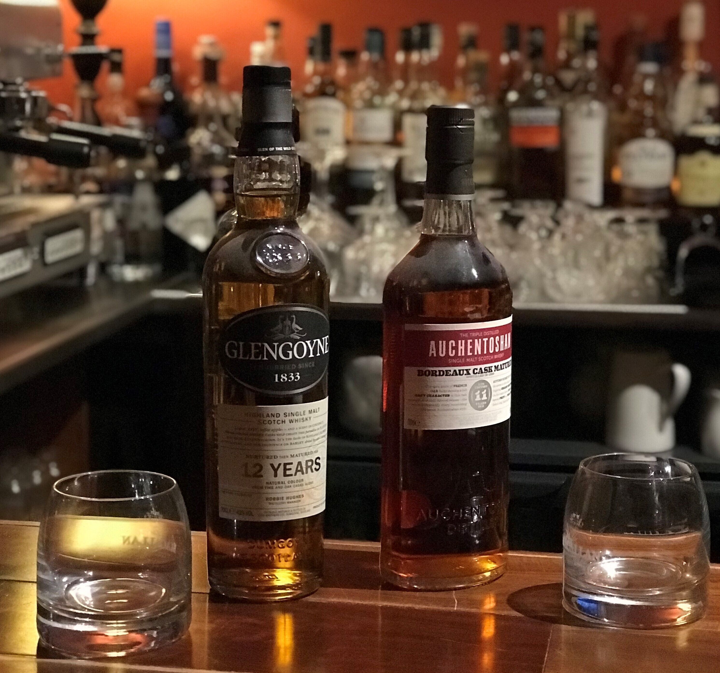 A bar with bottles of whisky and glasses.