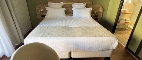 A hotel room with a large bed, a chair, and a small table.