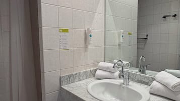 A modern bathroom with a marble sink, a large mirror, and a shower area.