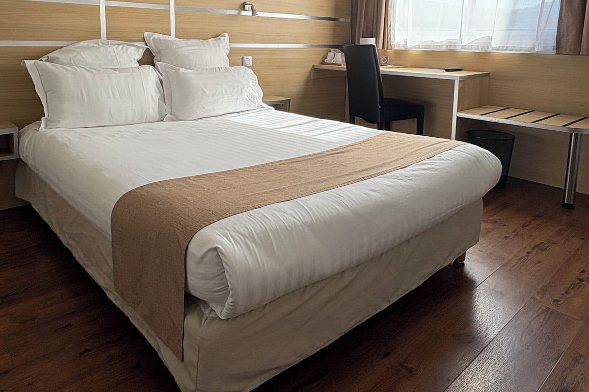 Una habitación de hotel con una cama grande, un escritorio y una silla.