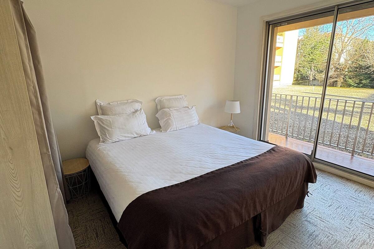 Un dormitorio con una cama grande, un ventanal con vistas al exterior y una araña.