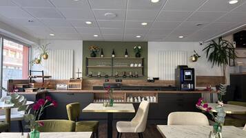 A modern cafe with a wooden counter, seating area, and decorative plants.