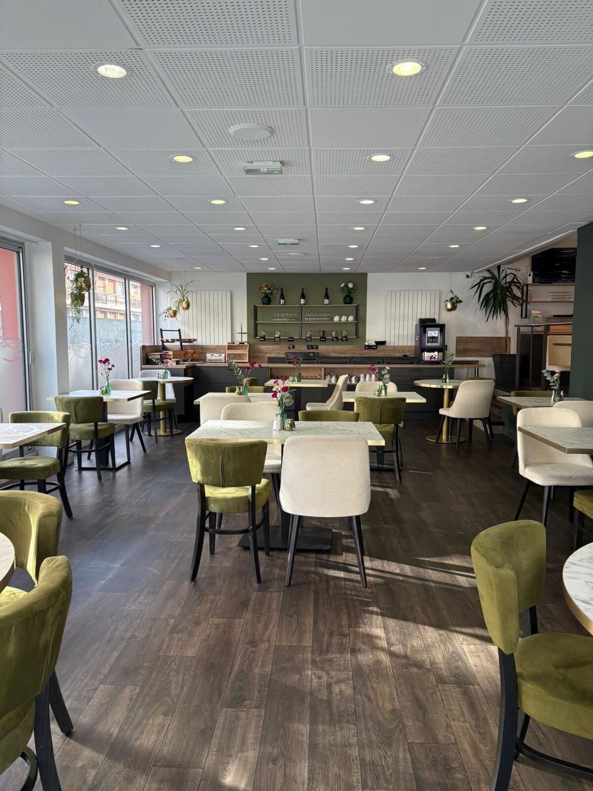 A spacious restaurant with high ceilings, recessed lighting, and a variety of seating arrangements including tables and chairs.