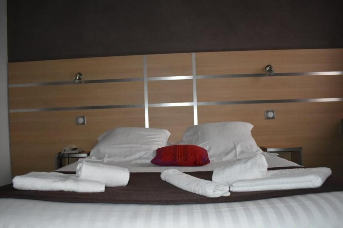 A hotel room with a large bed, two bedside tables, and a wooden headboard with a grid pattern.