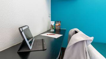 A conference room with a laptop on a stand, a tablet, a brochure, and a white jacket draped over a chair.