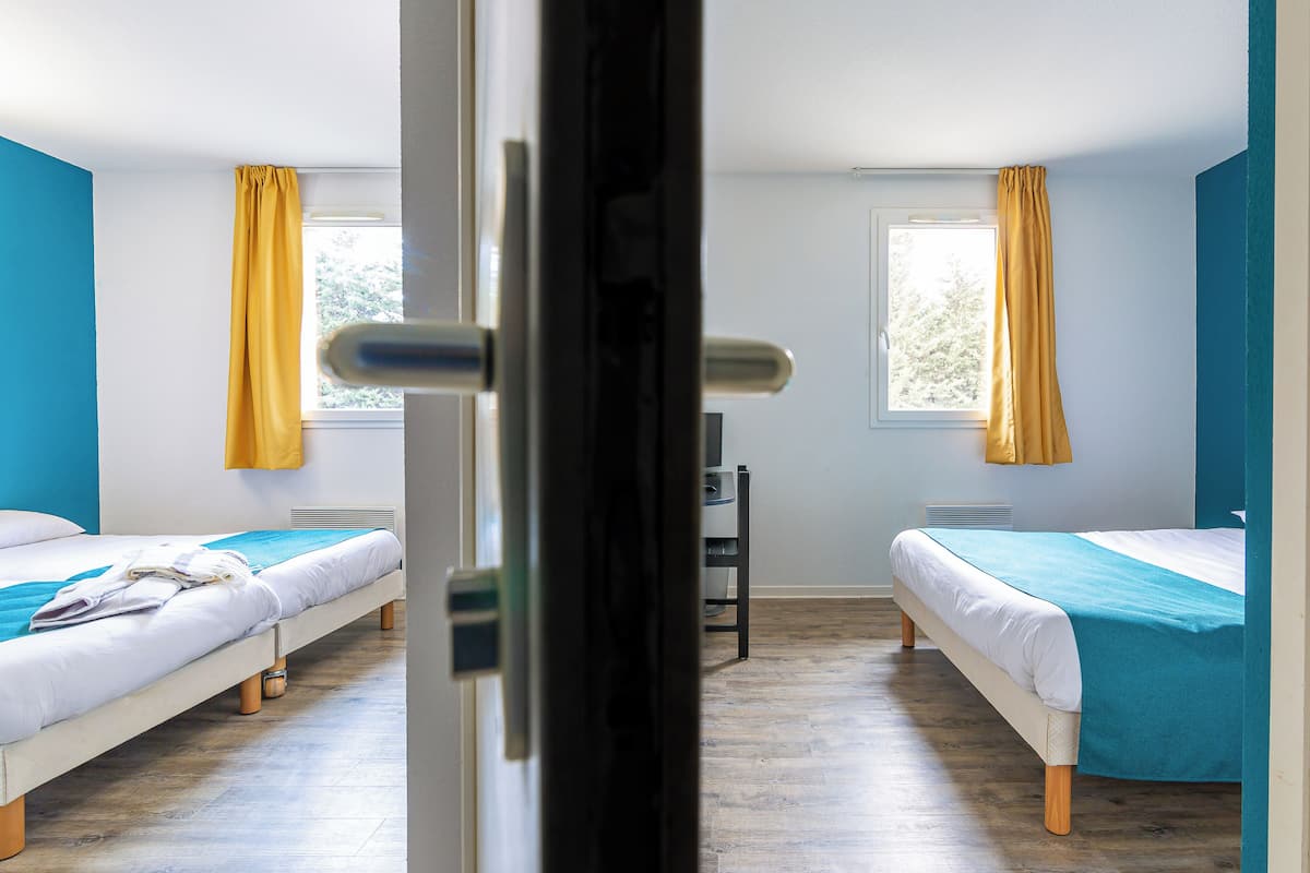 Une chambre avec deux lits, un radiateur et une fenêtre avec des rideaux.