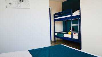 Dormitorio con literas, pared blanca y una obra de arte con una mariposa enmarcada.