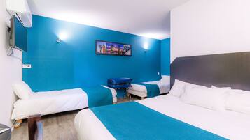 Hotelkamer met twee enkele bedden, een groot bed, een blauwe muur, een schilderij en een koffer op de vloer.