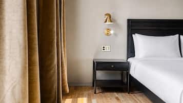 Una camera d'albergo con un letto, un comodino, una lampada a parete e una presa di corrente.