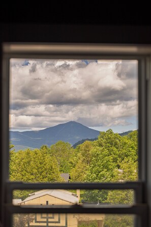 A view through a window of a mountain landscape with a building in the foreground. - Hotel St. Moritz (Lake Placid)