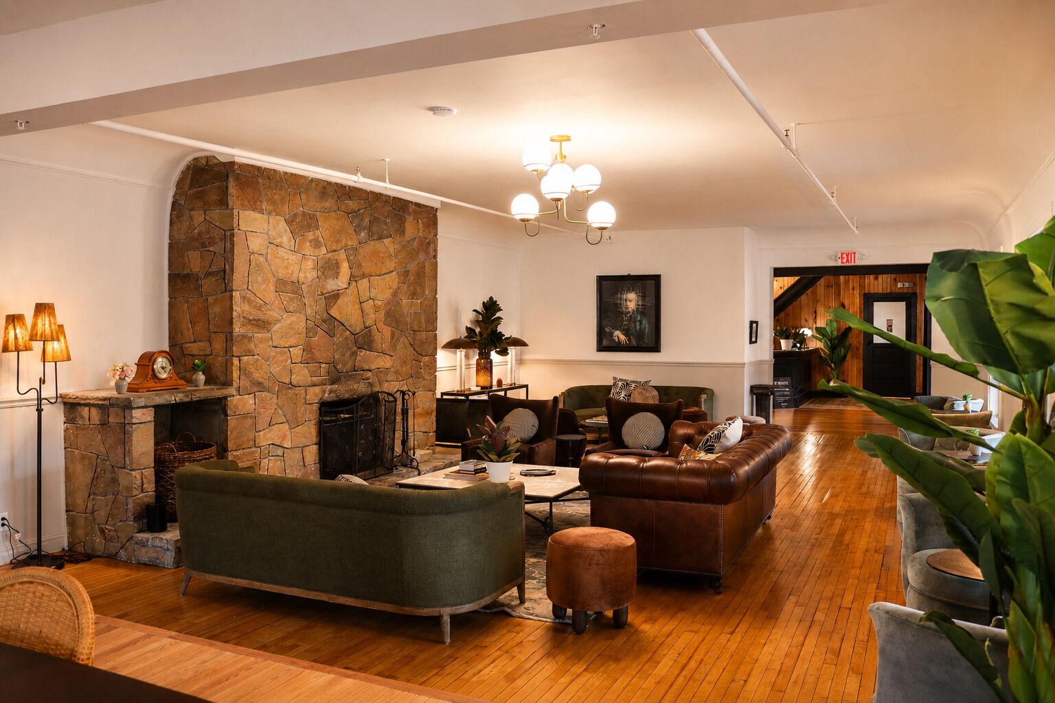 A spacious living room with a stone fireplace, leather sofas, and a wooden floor.