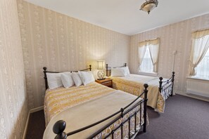 A bedroom with two beds, a nightstand, a lamp, and a ceiling light fixture. - Hotel St. Moritz (Lake Placid)