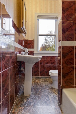 A bathroom with a sink, toilet, and window. - Hotel St. Moritz (Lake Placid)