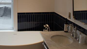 A bathroom with a bathtub, a sink, and a mirror.