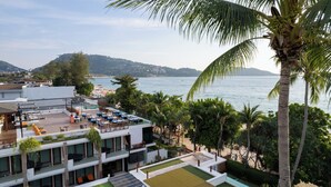 A rooftop terrace with outdoor seating, overlooking a beach and the sea. - La Flora Resort Patong (Patong)