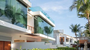 A modern building with large glass windows, a white facade, and a balcony. - La Flora Resort Patong (Patong)