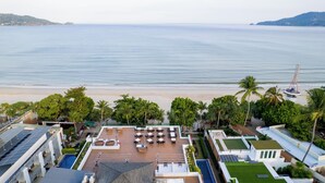 A resort with a pool, outdoor seating, and a view of the beach and ocean. - La Flora Resort Patong (Patong)