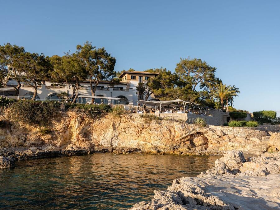 Un hotel frente al mar con costa rocosa, piscina y vistas al océano.