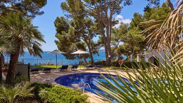 Una piscina al aire libre de temporada, sombrillas, tumbonas