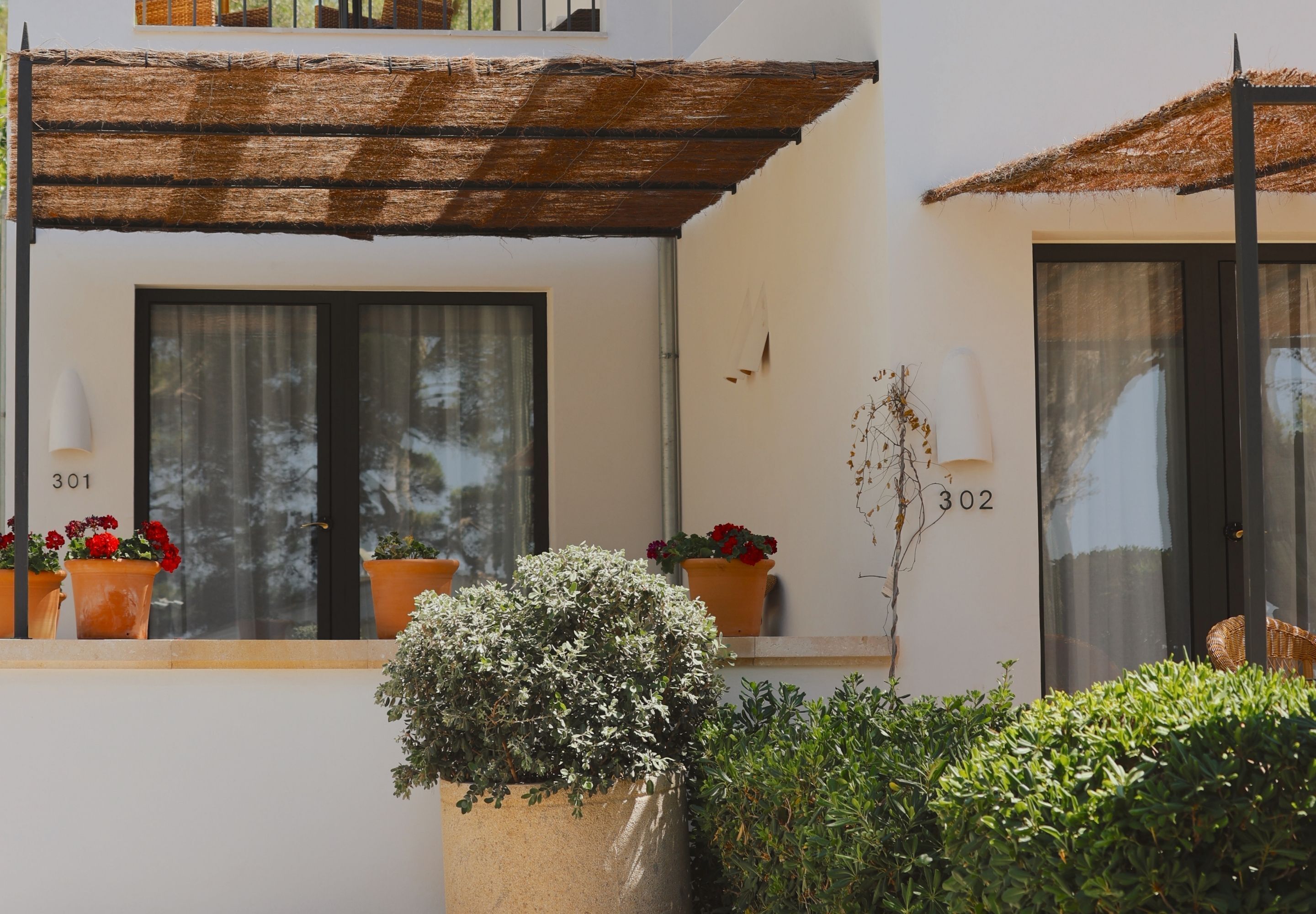 Un edificio con ventanas numeradas, una planta en maceta y una estructura de techo de paja.