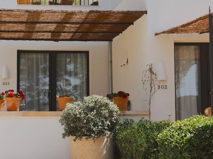 Un edificio con ventanas numeradas, una planta en maceta y una estructura de techo de paja.