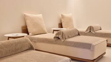 A minimalist room with three beds, each with a wooden headboard and a round side table.