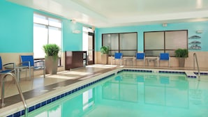 An indoor swimming pool with blue-tiled walls, seating areas, and potted plants. - SpringHill Suites by Marriott Chesapeake Greenbrier (Chesapeake)