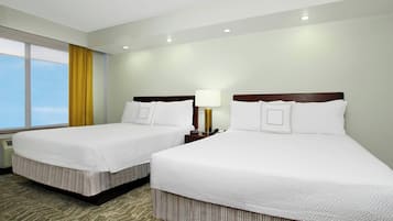 A hotel room with two beds, a window with curtains, a lamp, and a view of the sky.