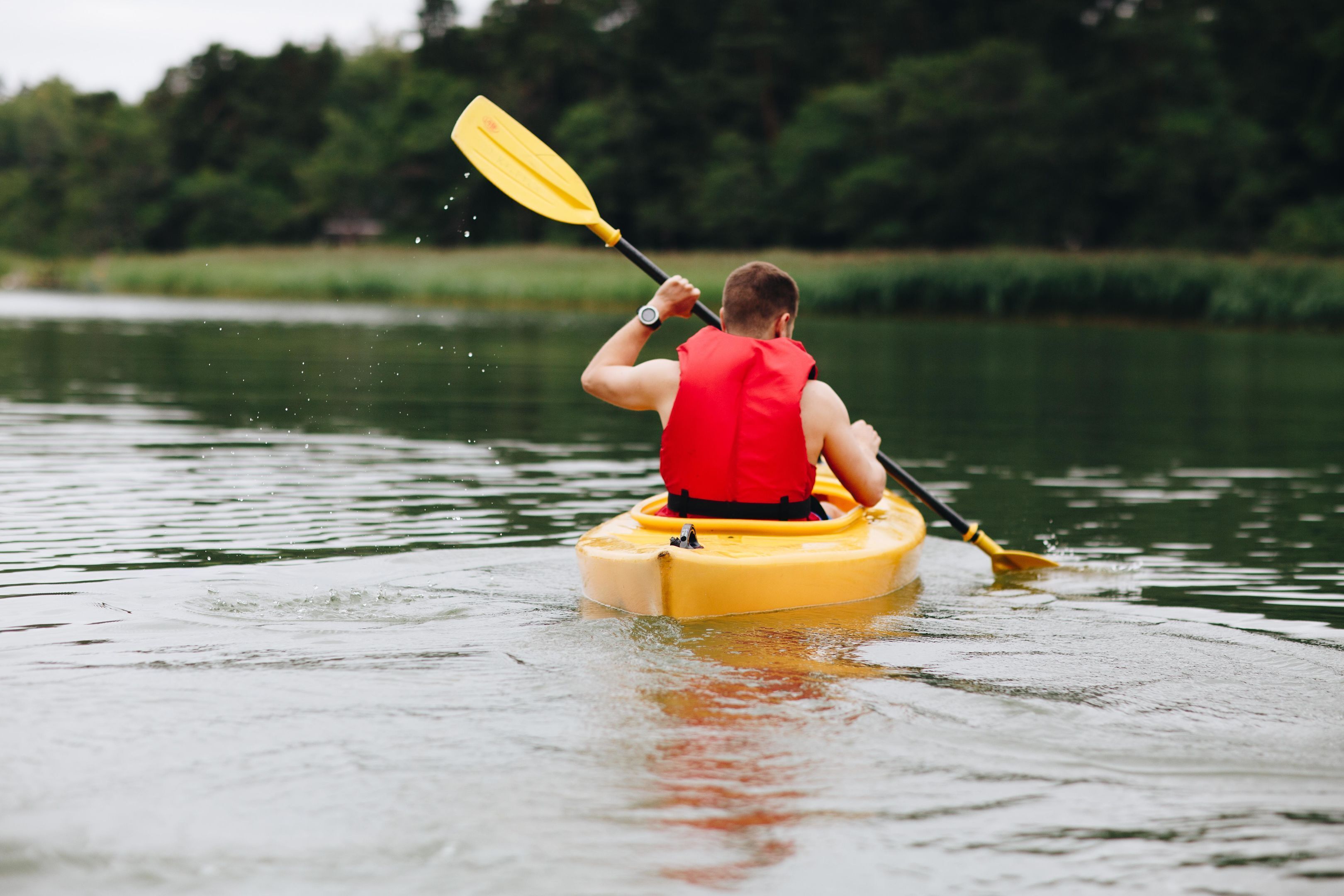 A person kayaking on a calm body of water.