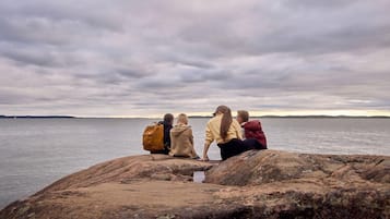 Four people sitting on rocks by a body of water.