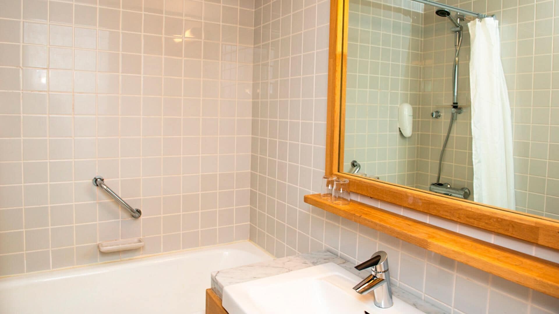 A bathroom with a bathtub, a sink, a mirror, and a shower area.