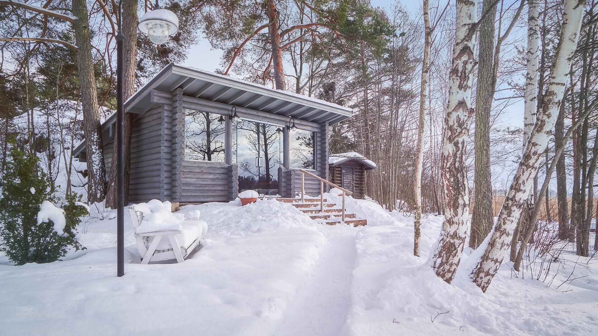 Une cabane en rondins dotée d’un porche couvert, d’un escalier menant à l’entrée et d’une épaisse couche de neige recouvrant la propriété.