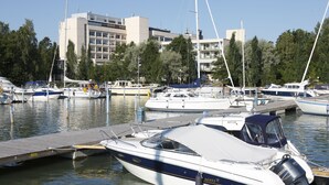 A marina with boats docked at wooden piers, surrounded by trees and buildings. - Ruissalo Spa Hotel (Turku)