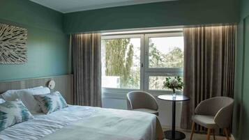 Ein Hotelzimmer mit einem Bett, zwei Stühlen, einem kleinen Tisch und einem Fenster mit Vorhängen.