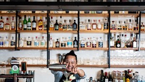 A bar with a bartender pouring a drink, shelves of liquor bottles, and glasses on the counter. - The Sebel Launceston (Launceston)
