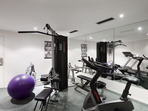A gym with exercise equipment, a large mirror, and a purple exercise ball. - The Sebel Launceston (Launceston)