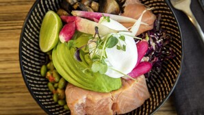 A bowl of food with various ingredients including avocado, radishes, and sprouts.