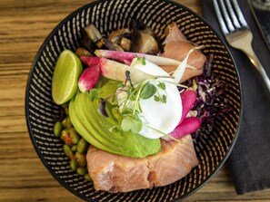 A bowl of food with various ingredients including avocado, radishes, and sprouts.
