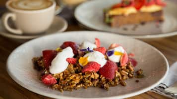 Un plato de postre con granola, fresas y crema batida.