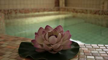 A lotus flower on a tiled surface near a pool.
