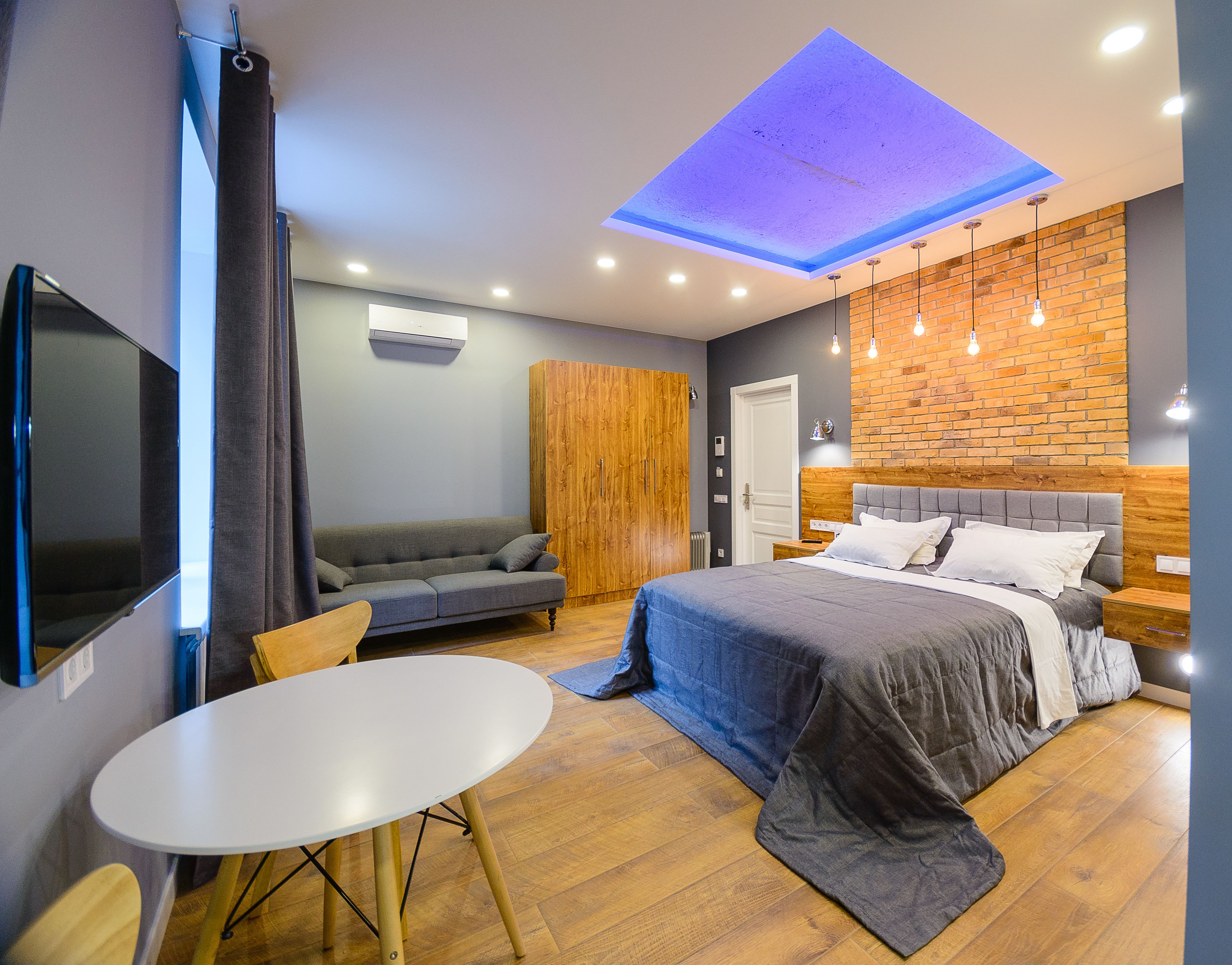 Un dormitorio moderno con cama, sofá, mesa y televisor.