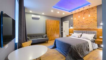 Un dormitorio moderno con cama, sofá, mesa y televisor.