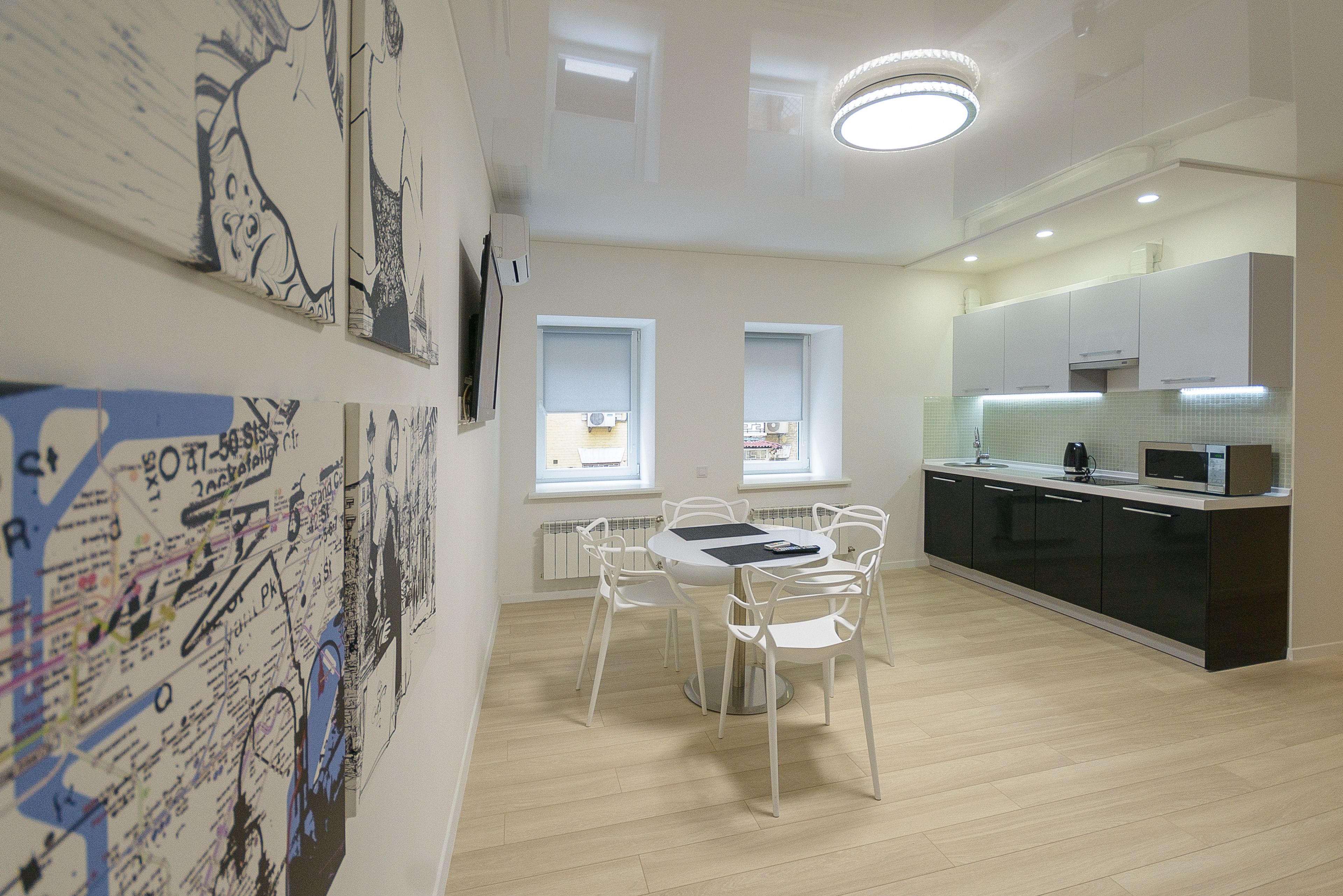 A modern kitchen with white cabinets, a microwave, and a dining area with a white table and chairs.
