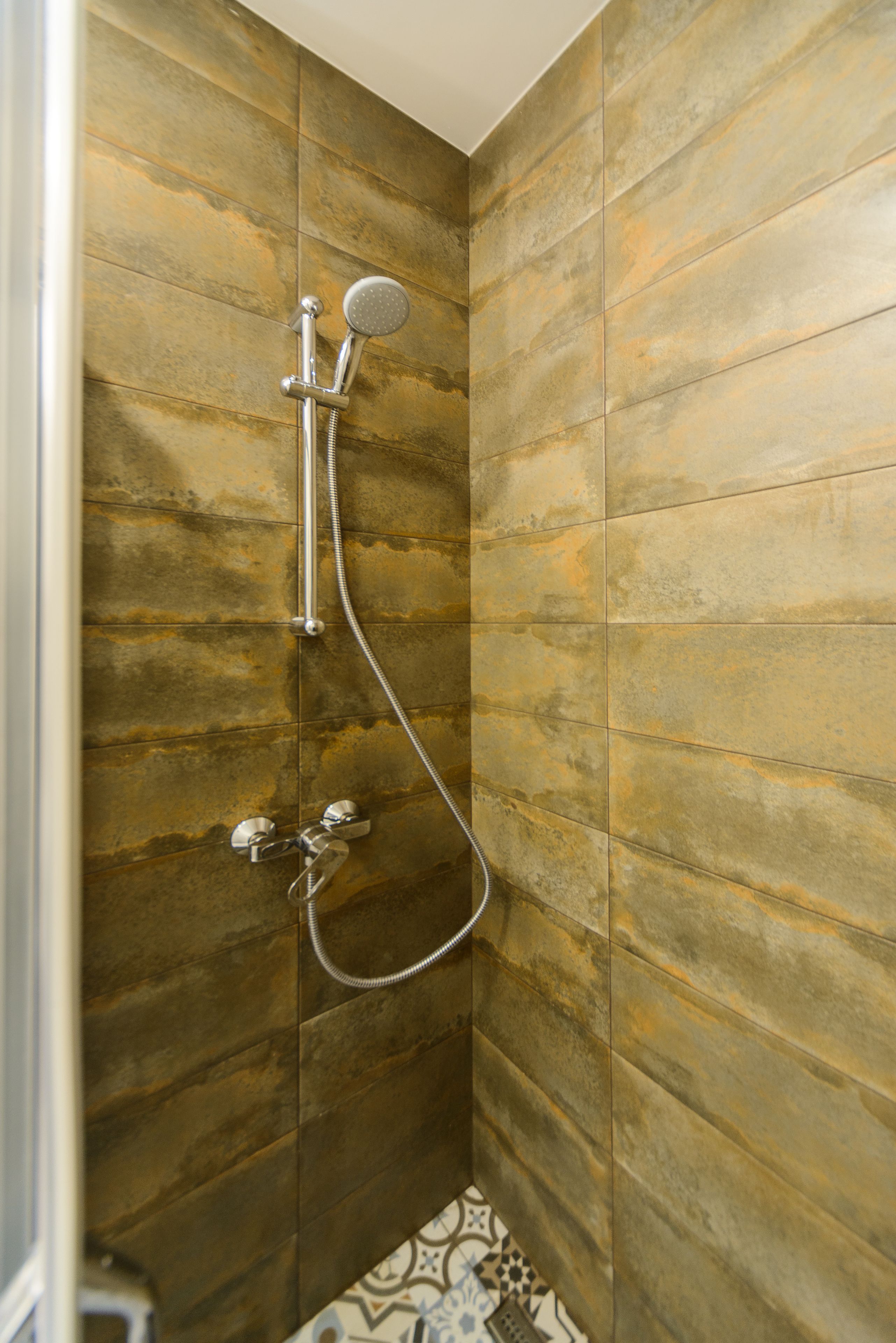 Eine Dusche mit Handbrause und Armaturen an der Wand.