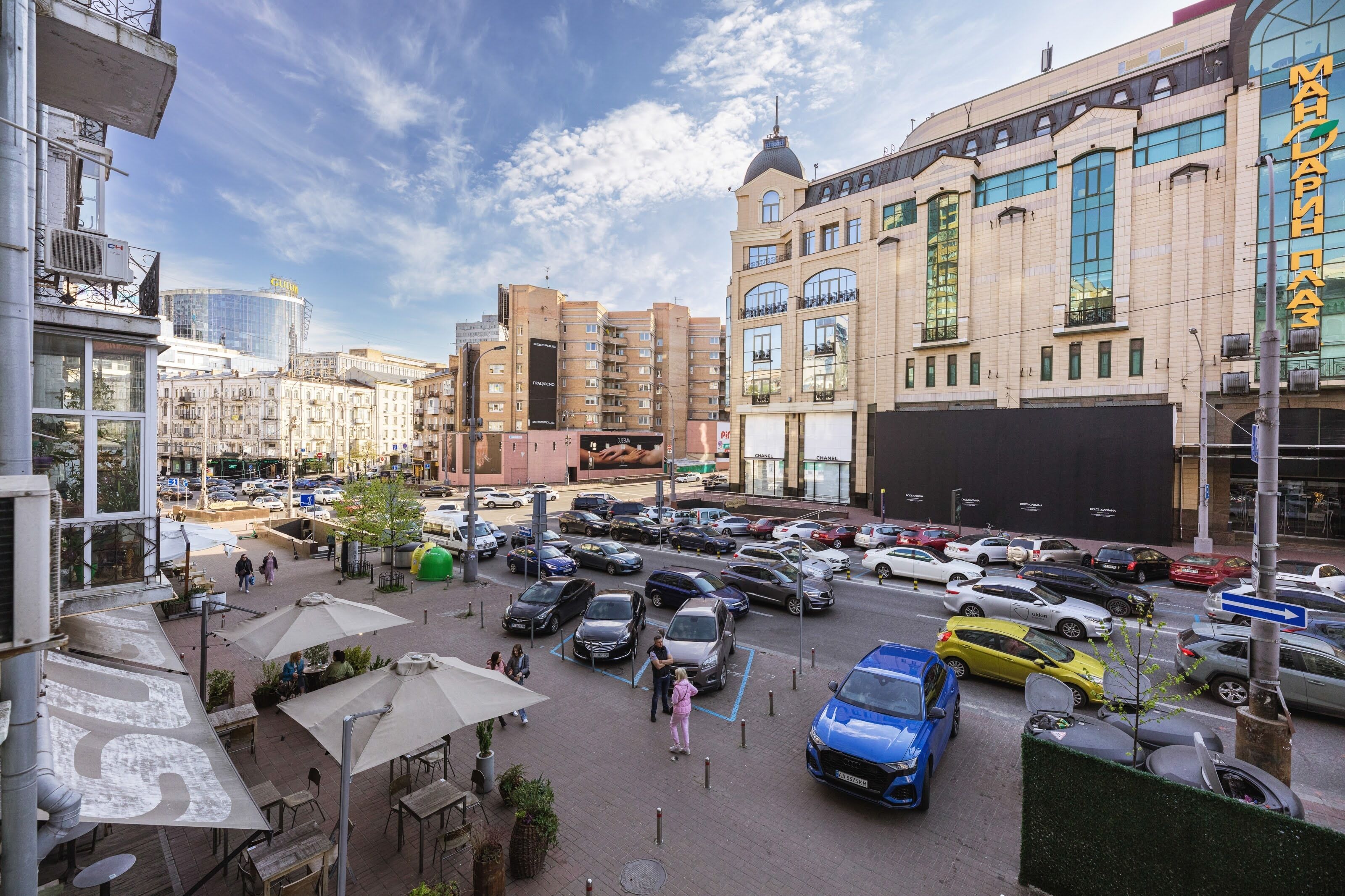 A busy urban street with parked cars and pedestrians.