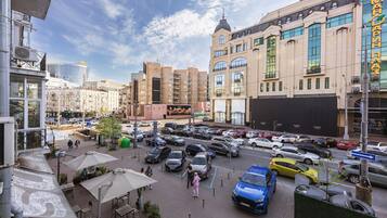 A busy urban street with parked cars and pedestrians.